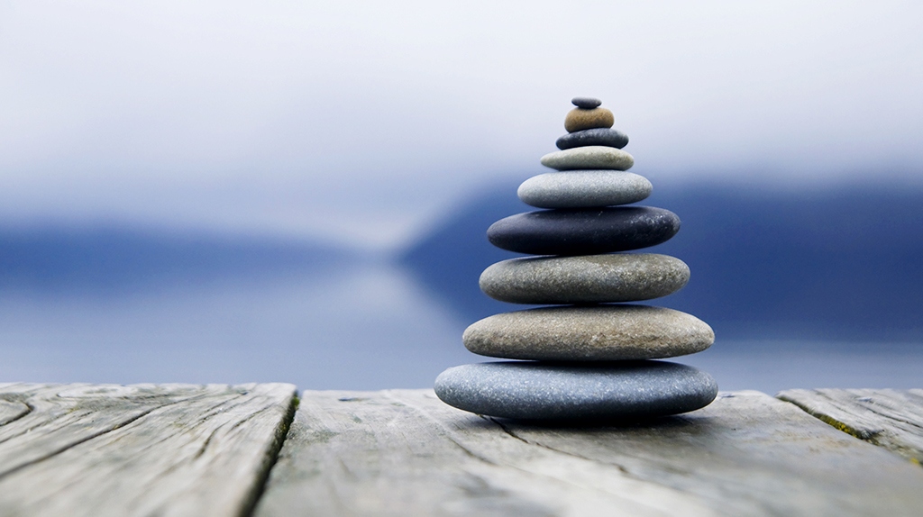 Zen balancing pebbles next to a misty lake.